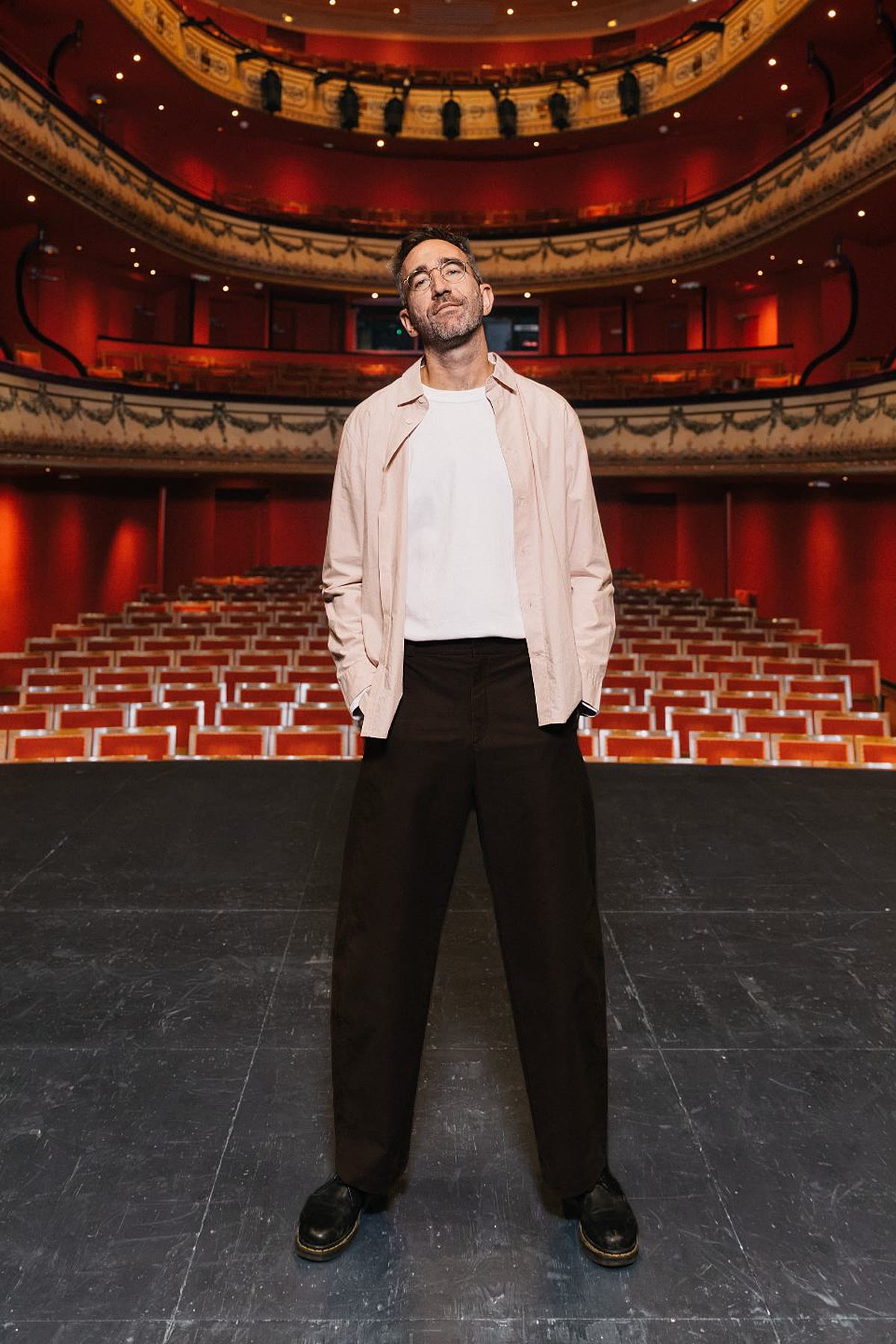 Bedou debout sur la scène d'un théâtre à l'italienne, sous la coupole dorée et le lustre